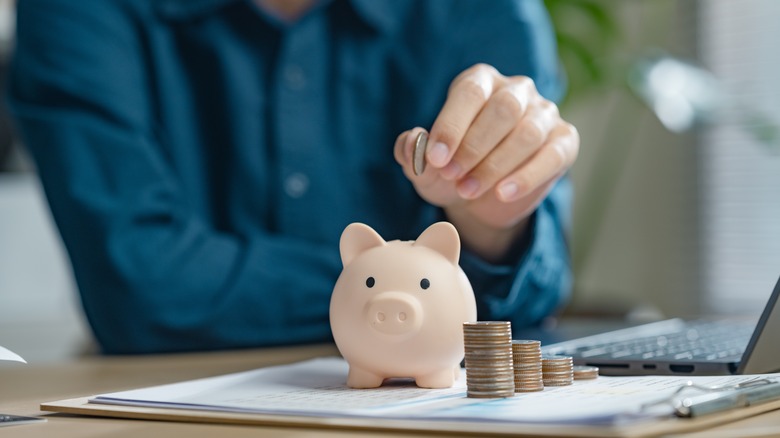 person putting coin in a piggy bank