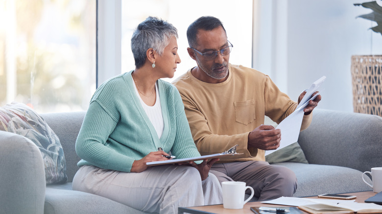 Mature couple in living room looking at paperwork.
