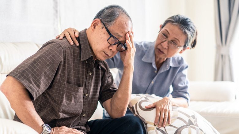 A stressed out older woman comforts her husband while he's upset