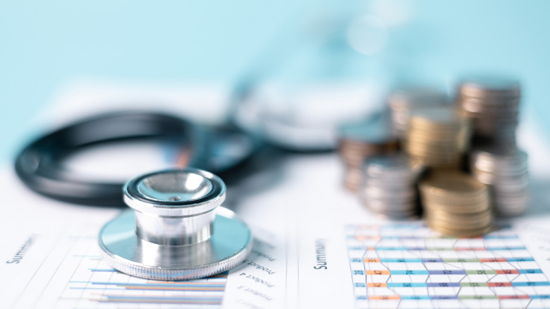 A stethoscope beside stacks of coins