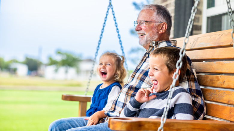 older man on swing chair with two children