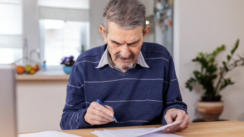 A senior adult man reviews bills