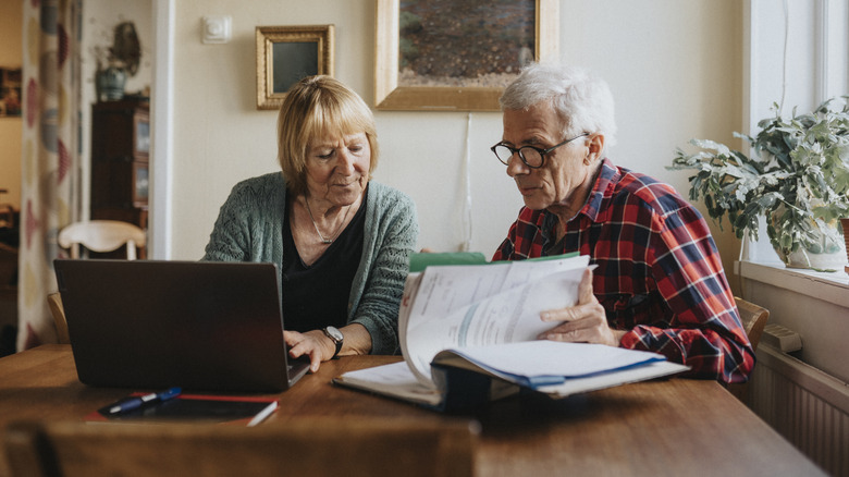 Senior couple reviewing documents with laptop