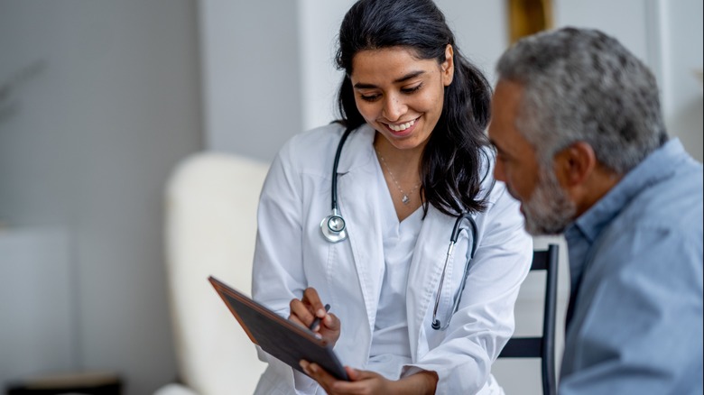 Doctor with a stethoscope reviewing a clipboard with an older male patient