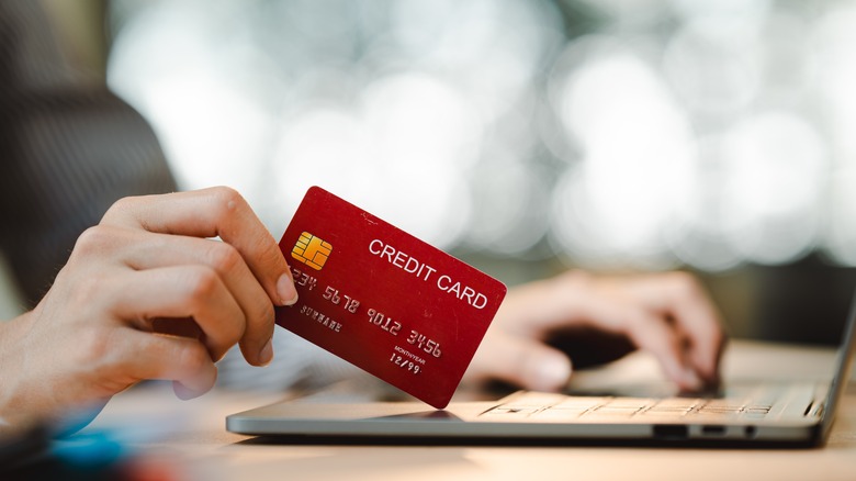 person at laptop holding a credit card