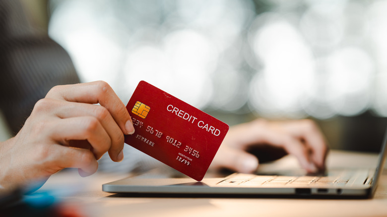 person at laptop holding a credit card
