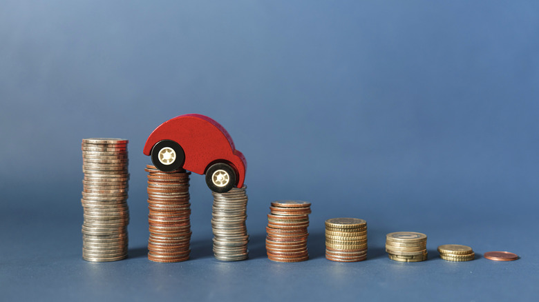 car figurine on decreasing stacks of coins