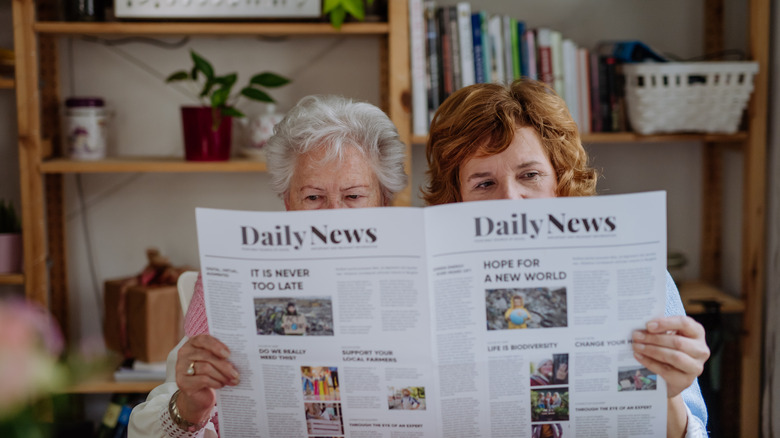 two people reading a newspaper