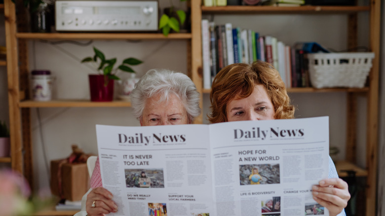 two people reading a newspaper