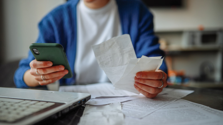 older person holding bills and a cell phone