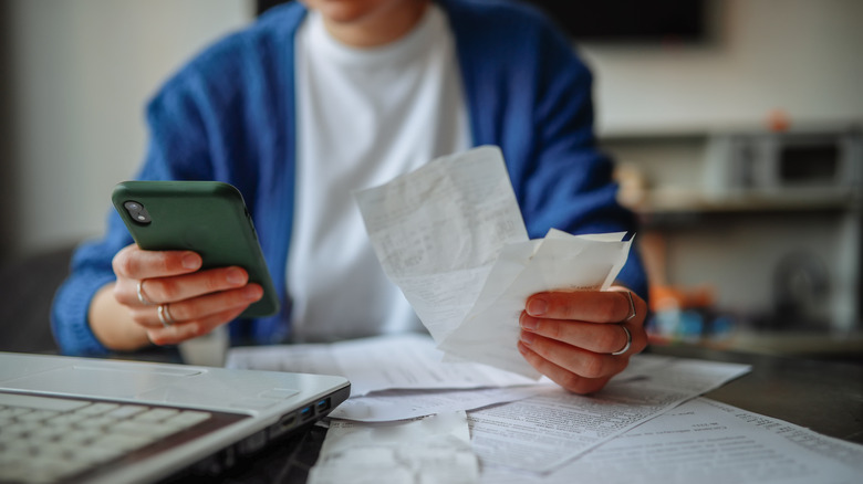 older person holding bills and a cell phone
