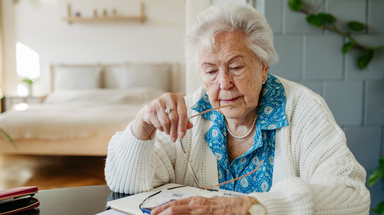Old woman with white hair looking over her bills
