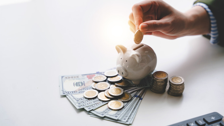 a hand places a coin into a piggy bank