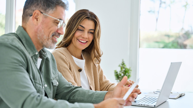 a middle-aged couple sitting at a computer