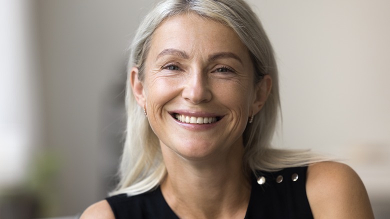 Portrait of woman about 60 who has long grey hair and is smiling