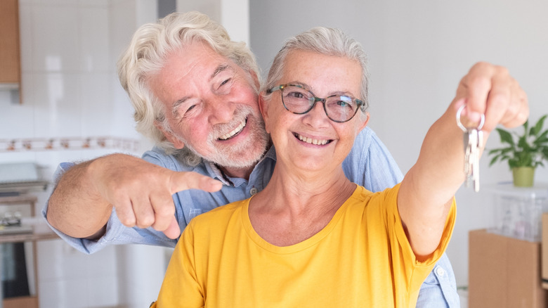 Cheerful senior couple hug enjoys moving into a new home