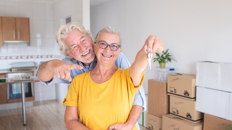 Cheerful senior couple hug enjoys moving into a new home