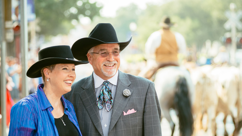 Older couple holding hands and wearing cowboy-style hats
