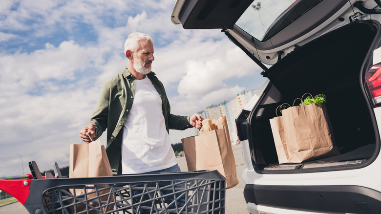 A senior man loading up the trunk of his car with groceries.