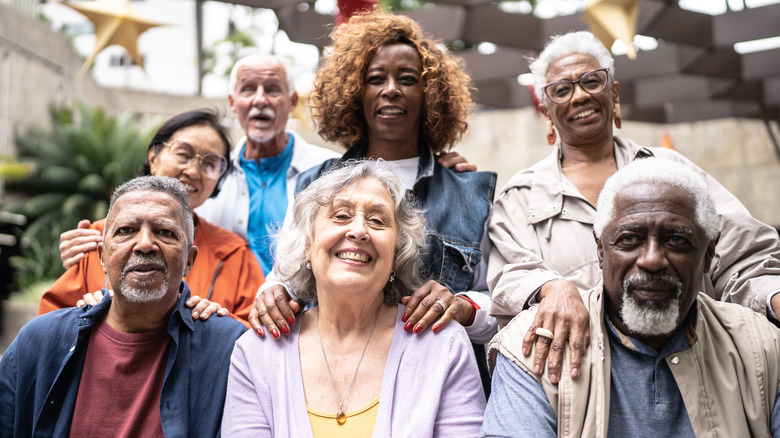 A diverse group of smiling seniors outdoors on a sunny day.
