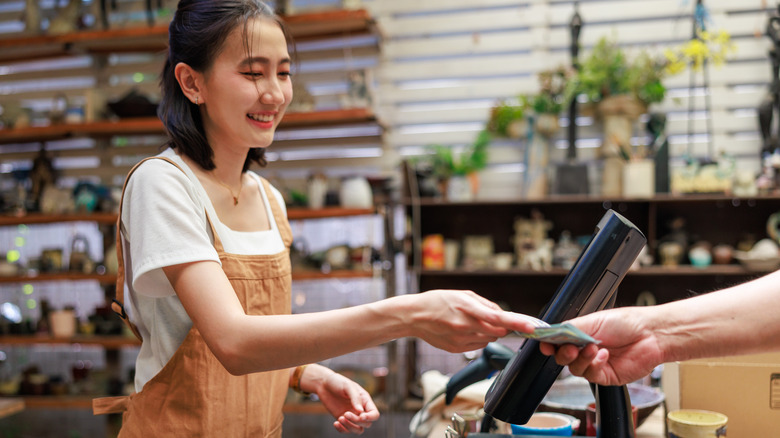 A young woman accepting cash payment at a cash register