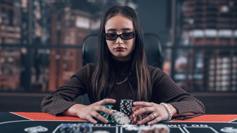 Woman sitting at poker table pulling a pile of poker chips toward her