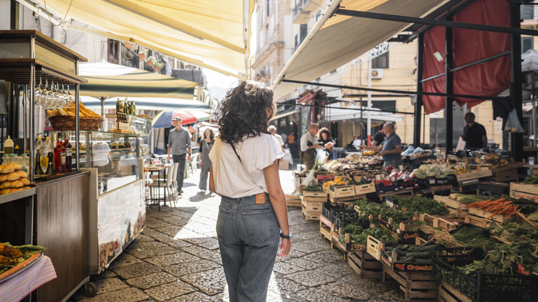 Woman walking through old town streets with stalls on either side