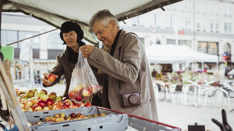 Tourist couple shopping for apples in bustling market