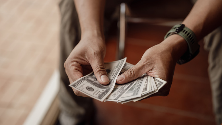 Man counting a collection of 100 dollar bills