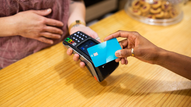 Merchant hand holds out card reading machine for customer's credit card