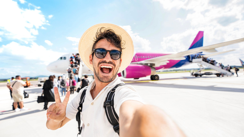 man on tarmac taking selfie before boarding plane