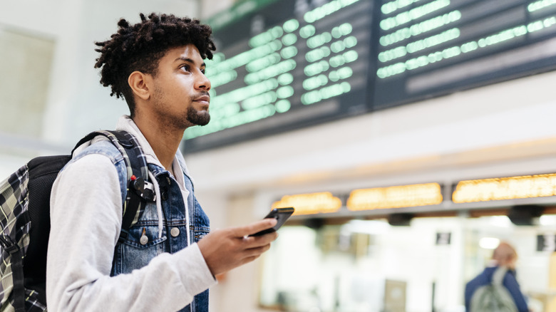 man looking at airport departures board