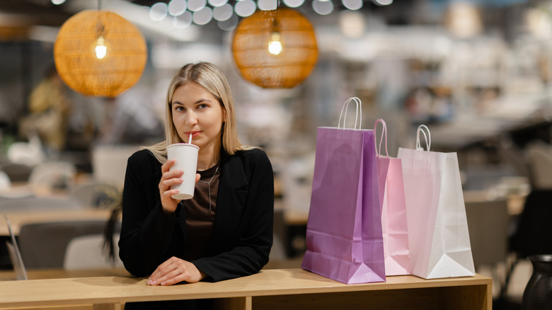 person sitting with a coffee and shopping bags
