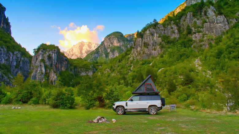 A car with a rooftop tent parked alone in an outdoor area in the mountains