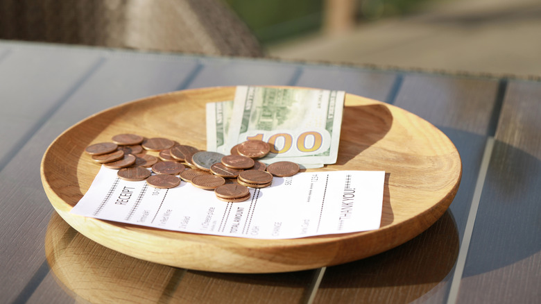 Wooden plate with payment for order and receipt on table