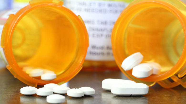Two prescription bottles on their side, with white pills pouring out