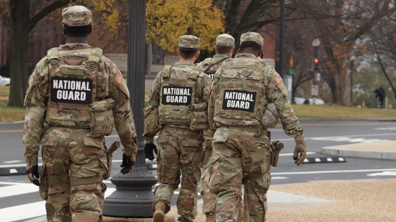 National Guard soldiers in camouflage uniforms walking along a city street