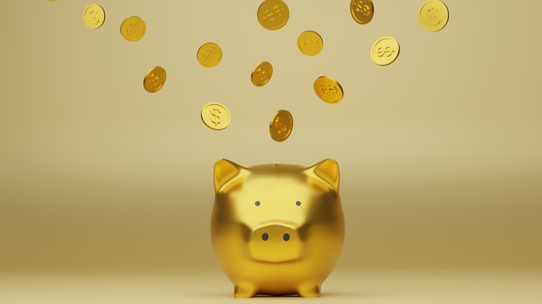 Gold coins going into a gold piggy bank