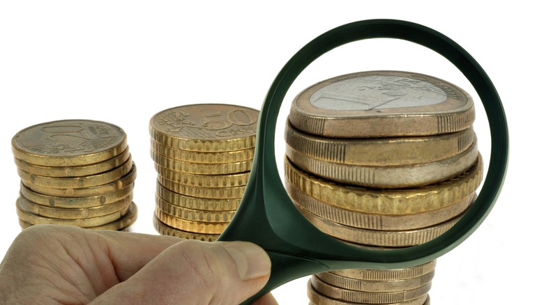 Stacks of Euros and european currency under a magnifier.