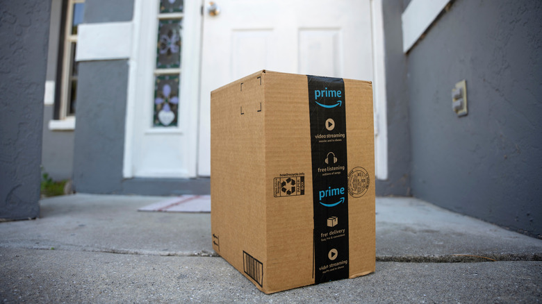 Amazon Prime package box with purchased online products delivered in front of house door.