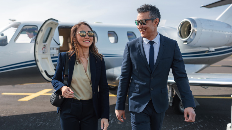 A couple walking away from a private jet.