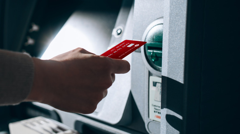 A person inserting a debit card into an ATM machine.
