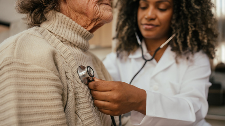 Doctor using stethoscope on an older patient.