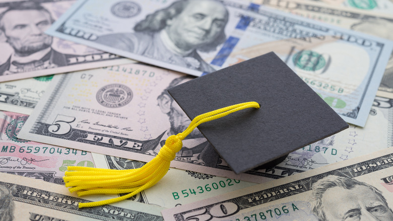 graduation cap laying on top of a pile of cash