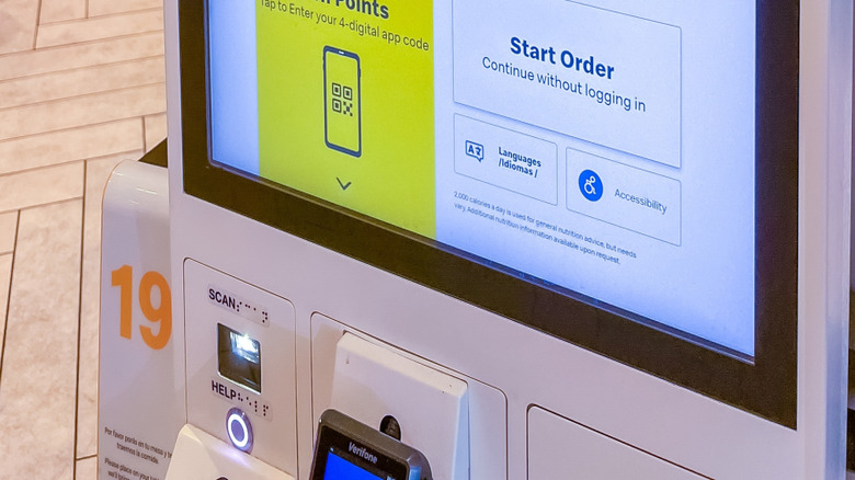 McDonald's self-service kiosk features a colorful rewards program display, encouraging customers to log in and order with copy space