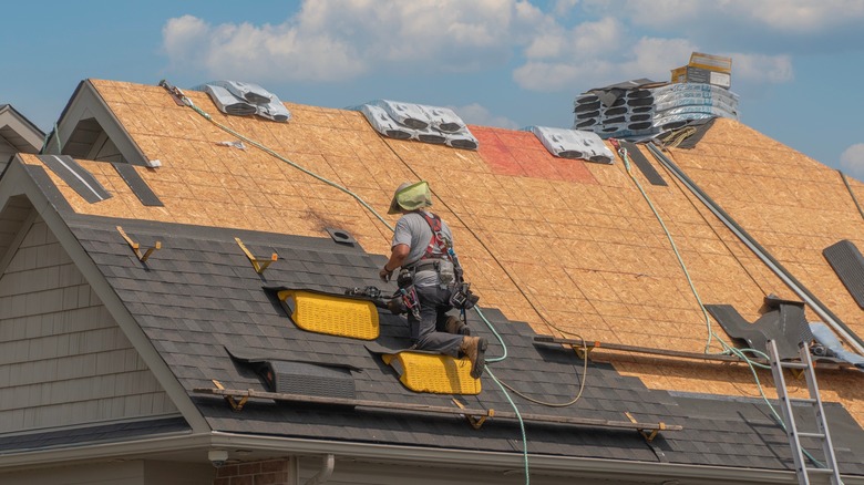 Roofers completely replace old asphalt shingle roof during summer.