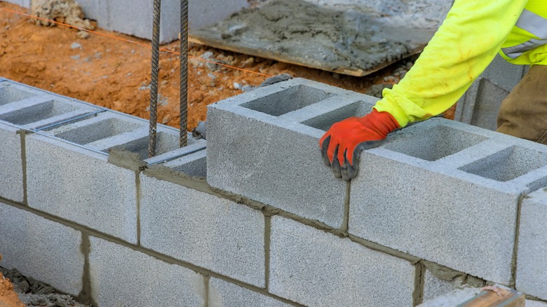 Worker carefully places concrete blocks while constructing wall at construction site
