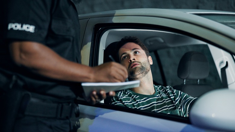 Man, officer and writing of ticket fine, registration and speeding for traffic warning.