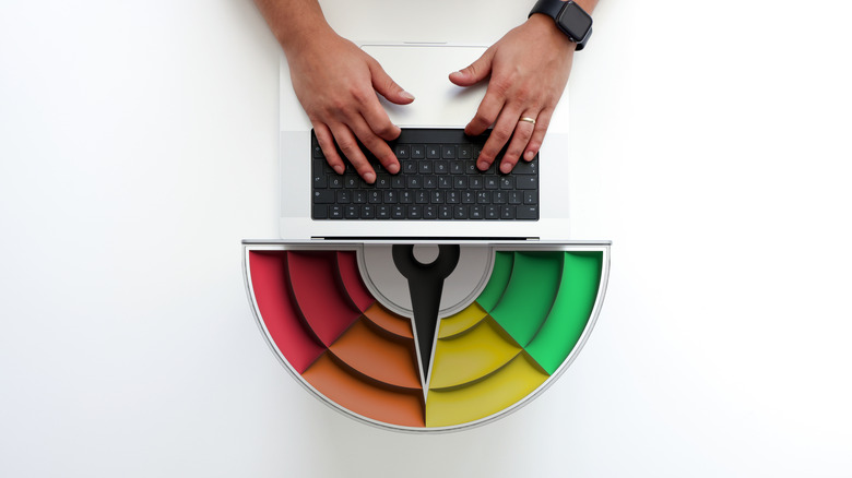 A person using a laptop on a desk with a credit score concept.