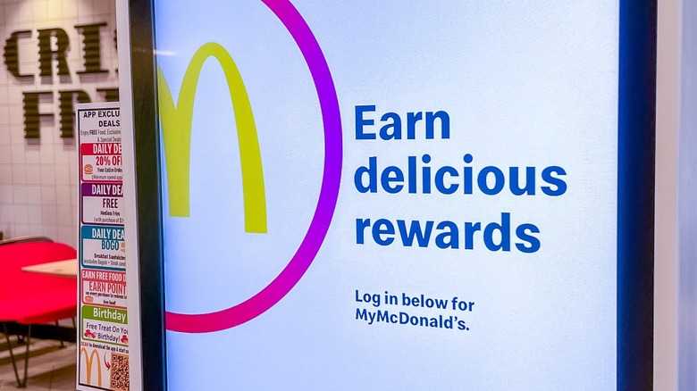 McDonald's self-service kiosk features a colorful rewards program display, encouraging customers to log in and order with copy space